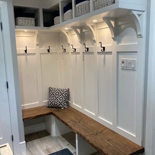 Custom mudroom with dark wood hooks panel and built-in storage